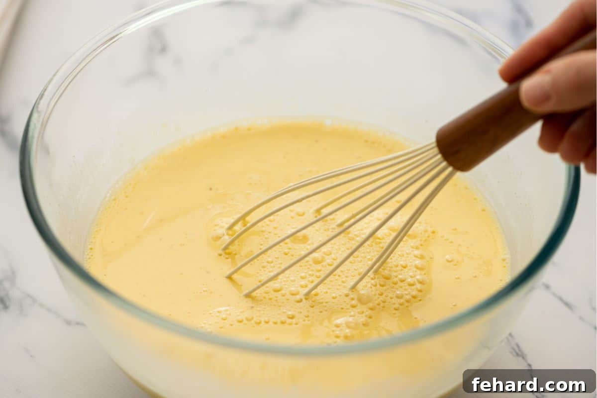 Whisk in bowl with eggs, cream, milk, and seasonings whisking together.