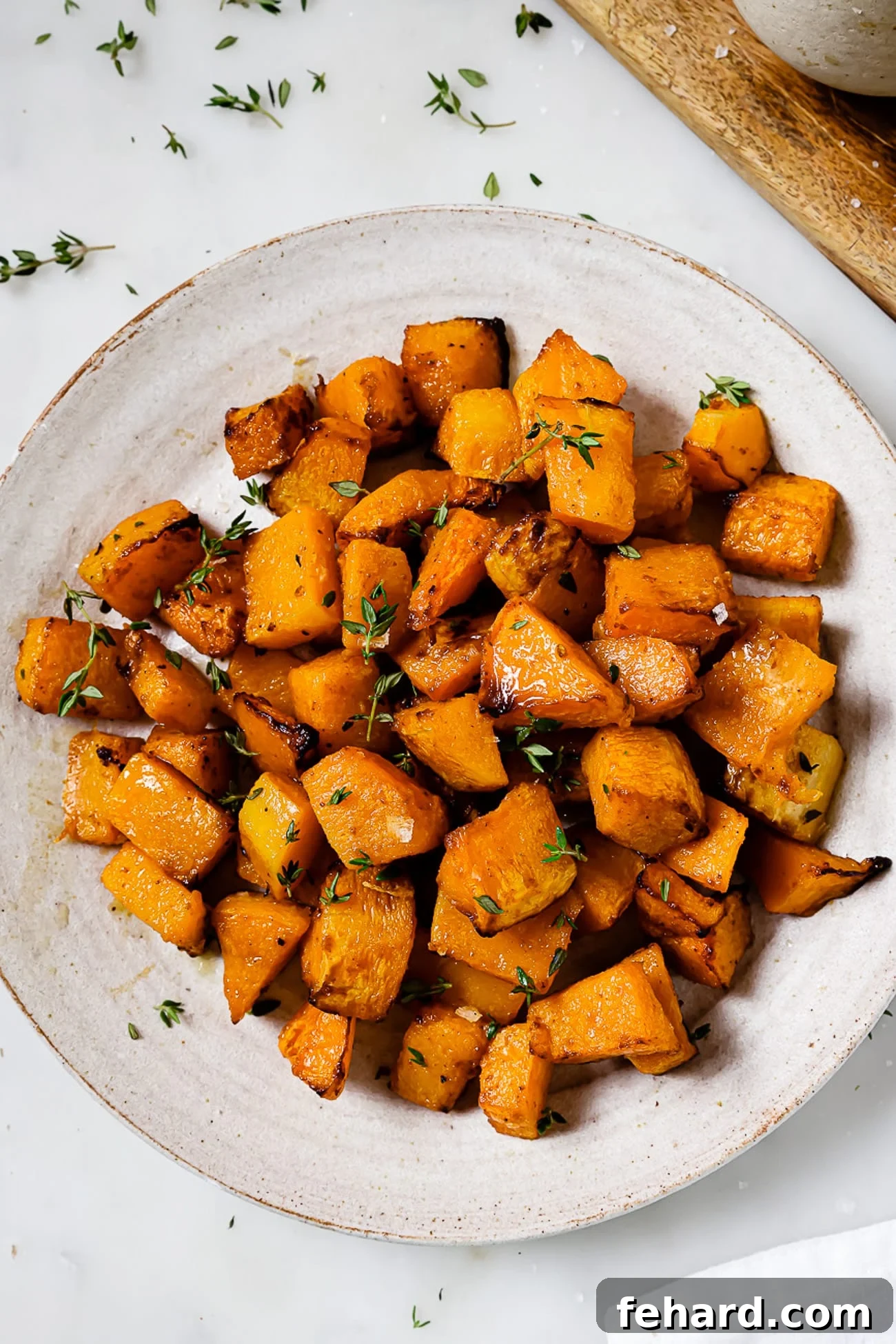 Golden Air Fryer Butternut Squash 2 A serving platter of air fryer butternut squash garnished with thyme.