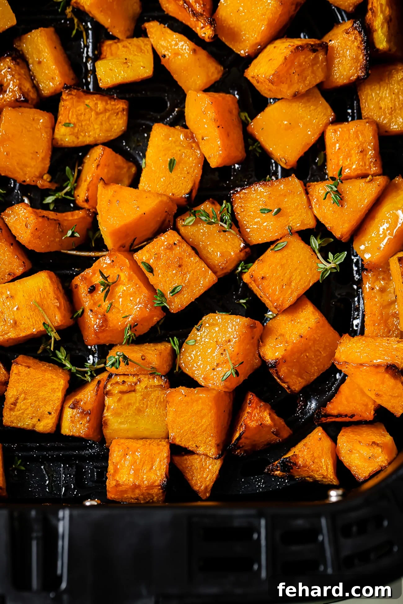 Golden Air Fryer Butternut Squash 11 A close up of air fryer butternut squash topped with fresh thyme.