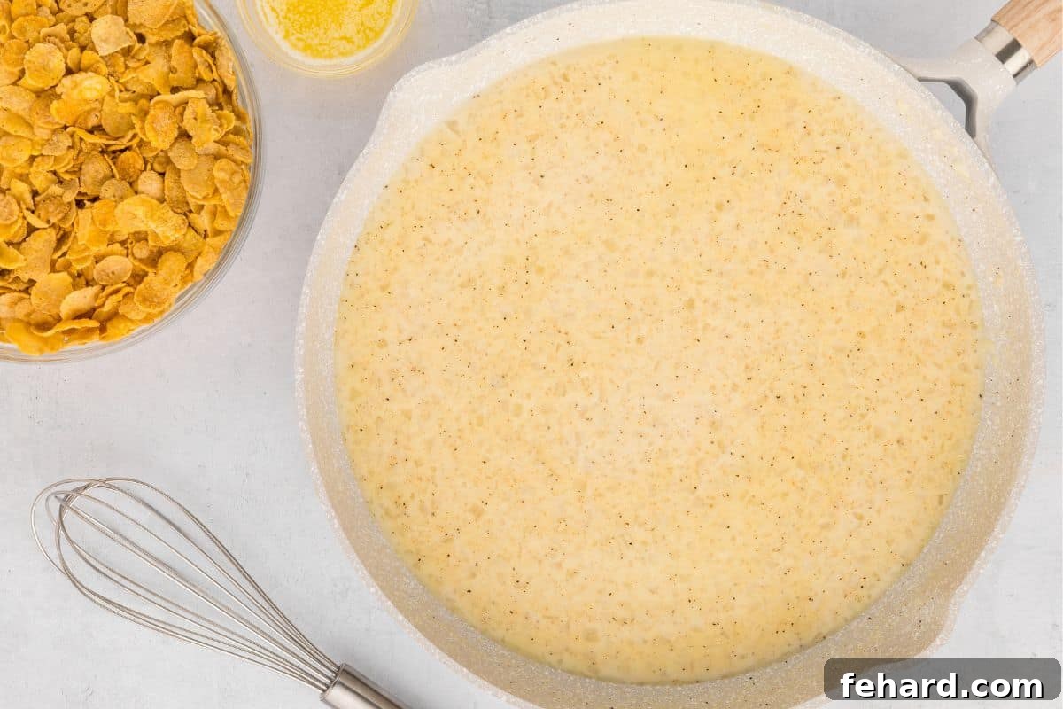 A saucepan on the stove with a creamy white sauce being continuously whisked, demonstrating the preparation of the homemade cream sauce from scratch.