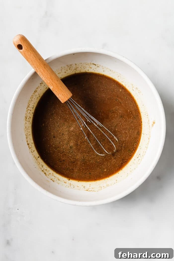 Melt-in-Your-Mouth Slow Cooker Pepper Steak 6 A small bowl of pepper steak sauce with a whisk in it.