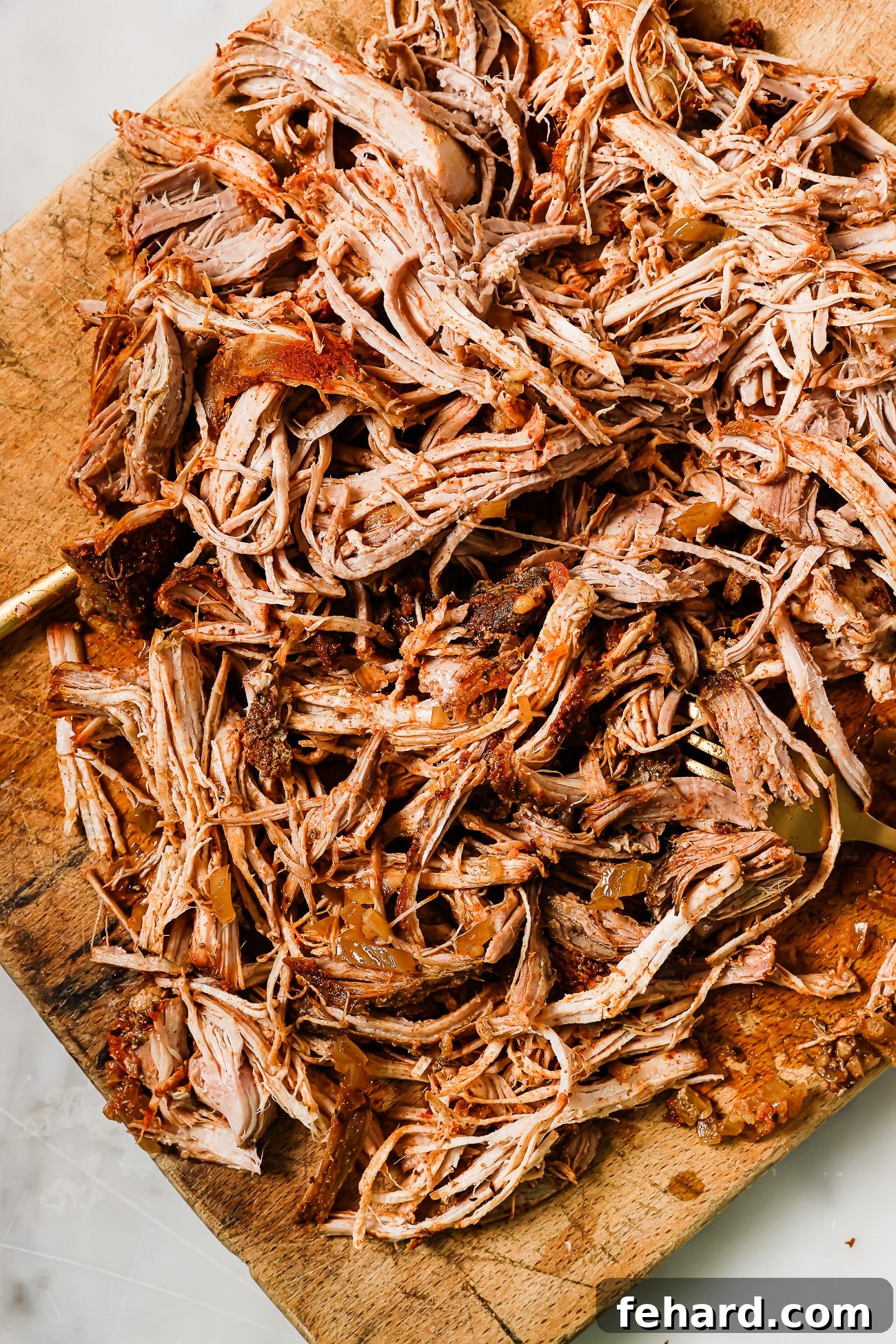 Melt-in-Your-Mouth Slow Cooker Pulled Pork 8 An overhead view of pulled pork on a wooden cutting board.