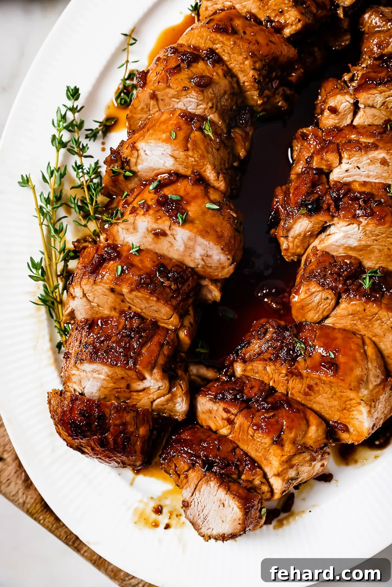 Two perfectly sliced honey garlic pork tenderloins, glistening with a savory glaze, arranged artfully on a white serving plate, ready to be enjoyed.