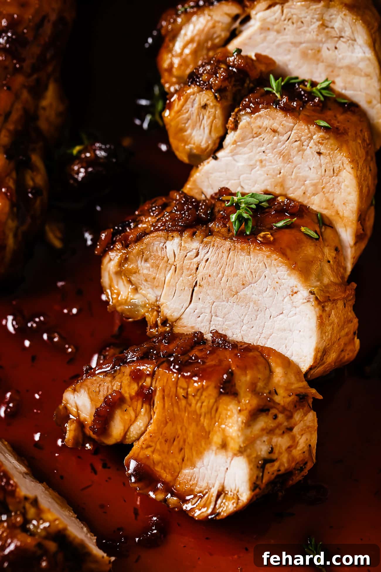 A close-up shot of perfectly sliced pork tenderloin, glistening with a rich honey garlic sauce, revealing its juicy, tender interior.