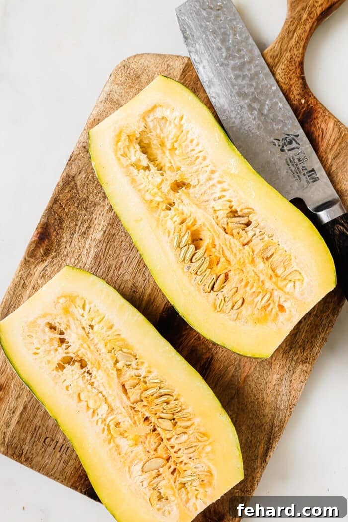 Caramelized Delicata Squash 4 A delicata squash cut in half on a wooden cutting board.