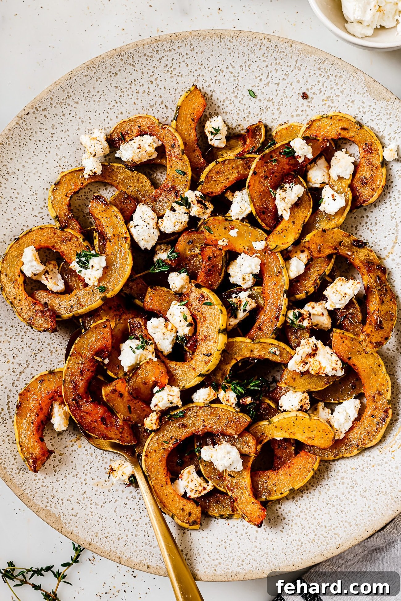 Caramelized Delicata Squash 9 Roasted delicata squash garnished with goat cheese on a white serving plate.