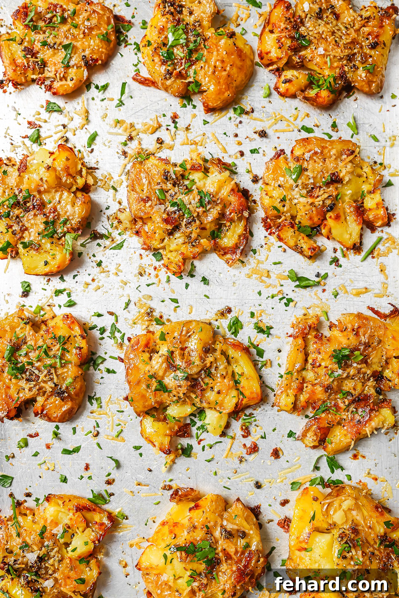Crispy Smashed Potatoes 10 Crispy, golden-brown smashed potatoes fresh from the oven, garnished with green herbs, displayed on a baking sheet.