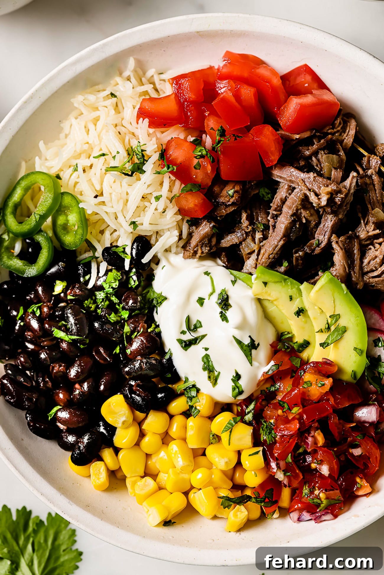 Smoky Barbacoa Bowl 4 A beautifully arranged Barbacoa Burrito Bowl, showcasing layers of tender barbacoa, fluffy rice, black beans, vibrant pico de gallo, sweet corn, and creamy avocado slices.