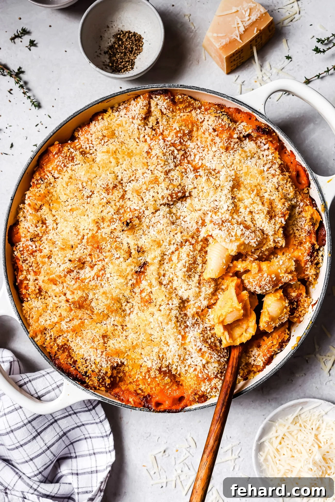 A vibrant, golden butternut squash mac and cheese in a white ceramic baking dish, photographed from above.