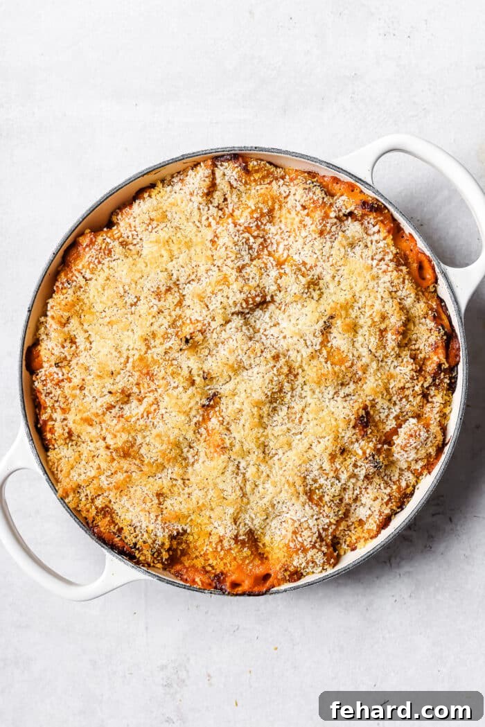 A golden-brown and bubbling butternut squash mac and cheese in a white skillet, fresh out of the oven, with a perfectly crispy topping.