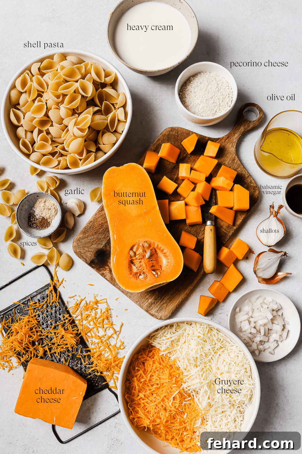 A selection of fresh, pre-measured ingredients like cubed squash, shallots, garlic, and grated cheese, arranged in small white bowls on a pristine countertop, ready for cooking.