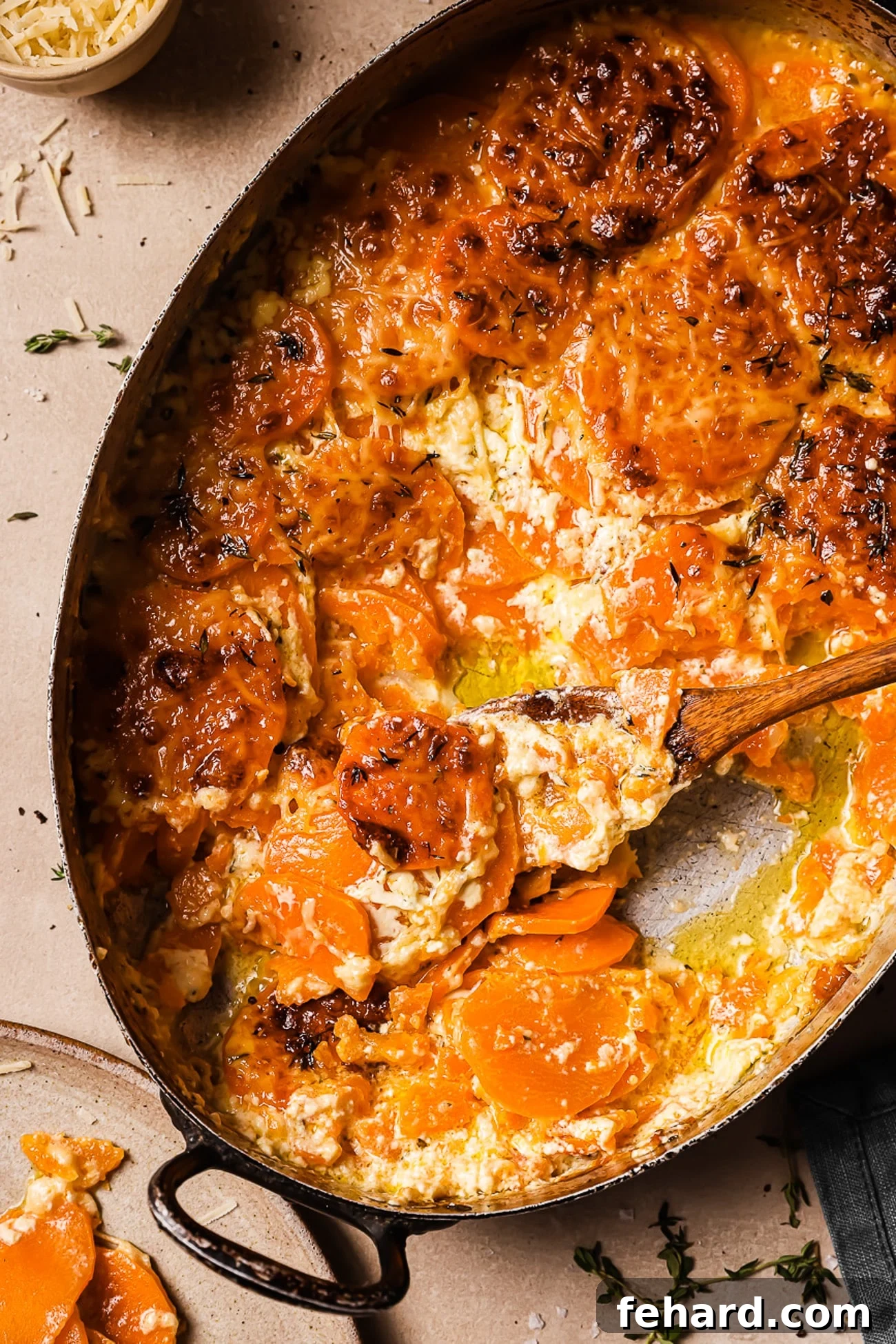 Golden Sweet Potato Bake 11 An overhead view of sweet potato gratin with a wooden spoon in it, showcasing the rich, creamy layers.