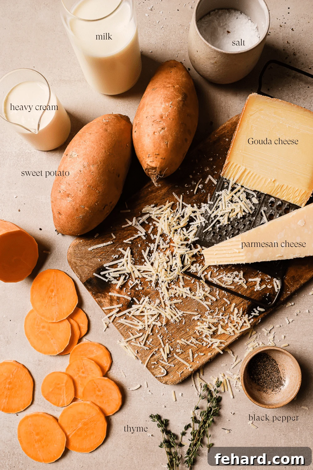 Golden Sweet Potato Bake 3 An overhead view of prepped ingredients on a wooden cutting board, including sliced sweet potatoes, cheese, and fresh thyme.