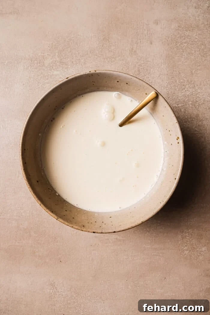 Golden Sweet Potato Bake 4 A bowl of milk and heavy cream with a spoon in it, ready for mixing.