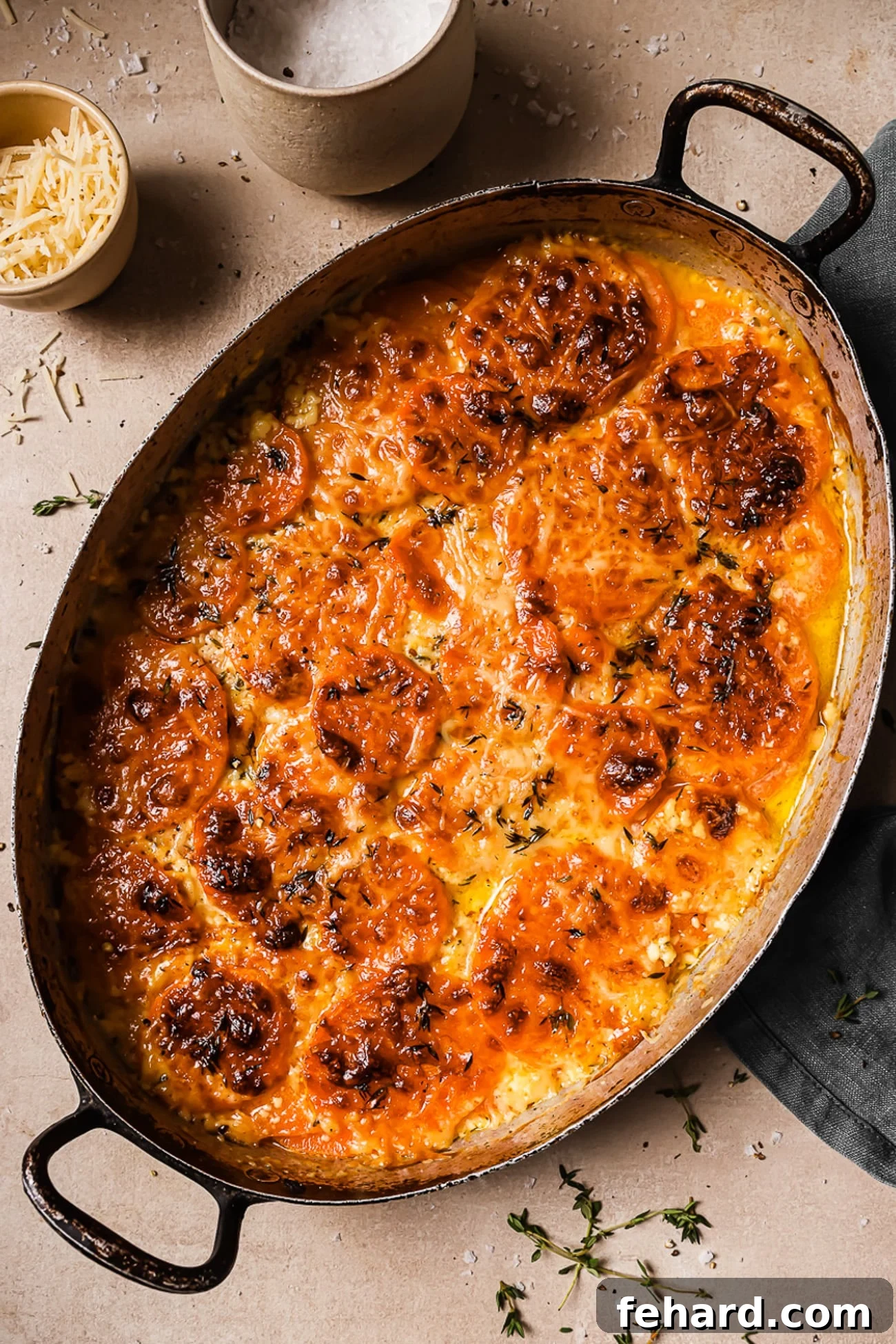 Golden Sweet Potato Bake 8 An overhead view of a perfectly baked sweet potato gratin in an oval baking dish, golden brown and bubbly, garnished with fresh thyme.