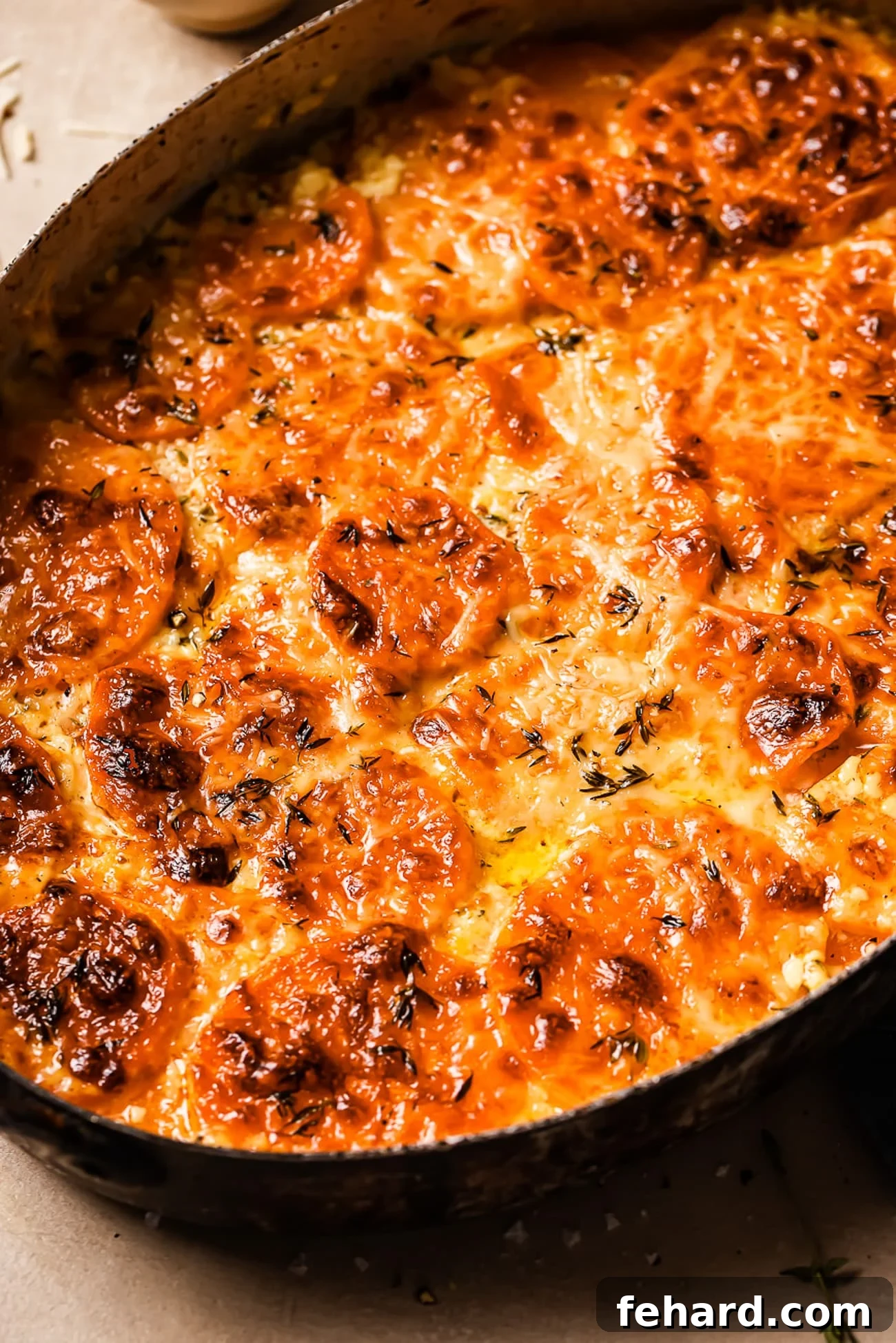 Golden Sweet Potato Bake 9 A closeup of sweet potato gratin in an oval casserole dish, showing the bubbly, golden-brown cheese topping and tender layers.