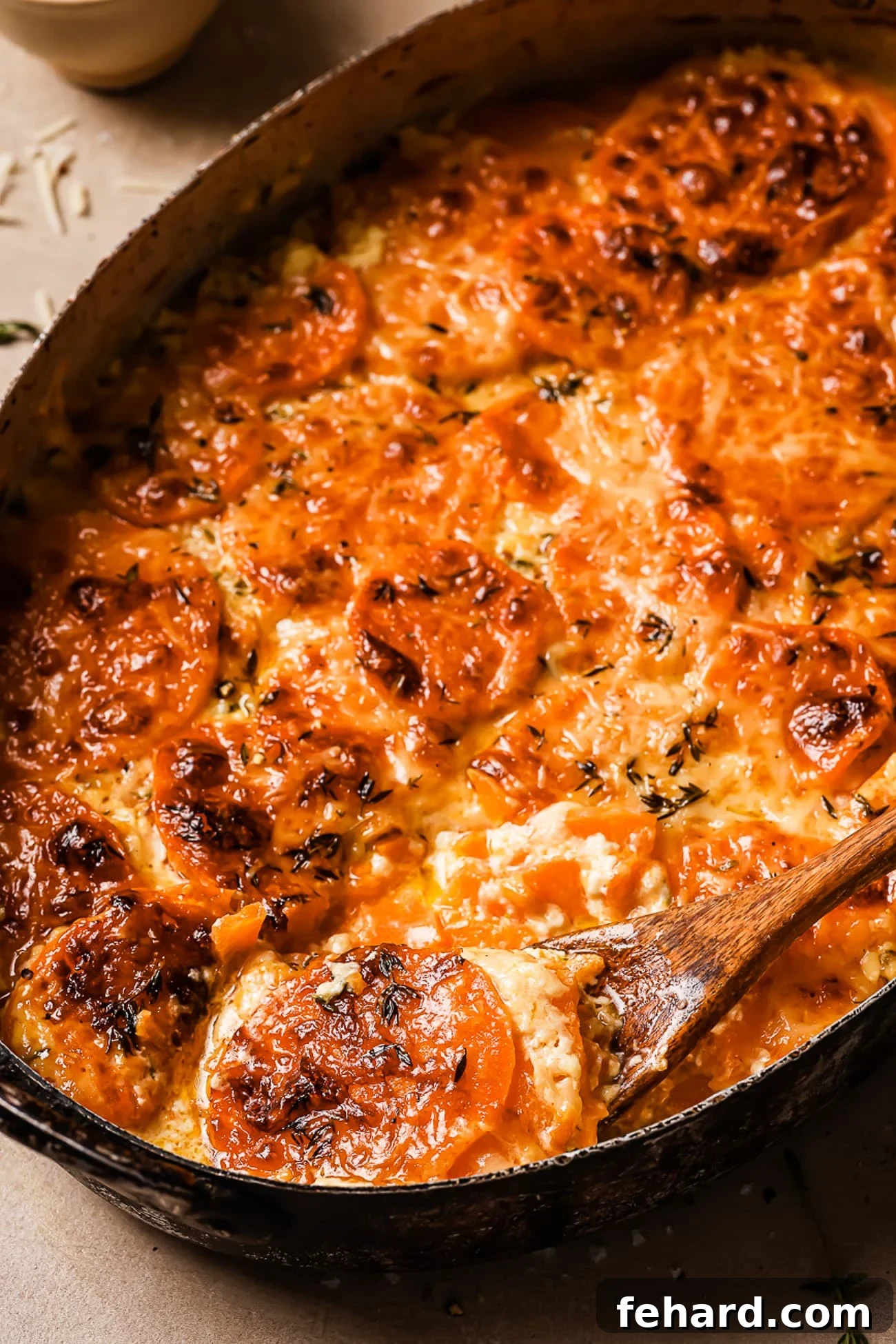 Golden Sweet Potato Bake 10 Sweet potato gratin in a baking dish with a wooden spoon taking a serving out, highlighting its creamy texture.