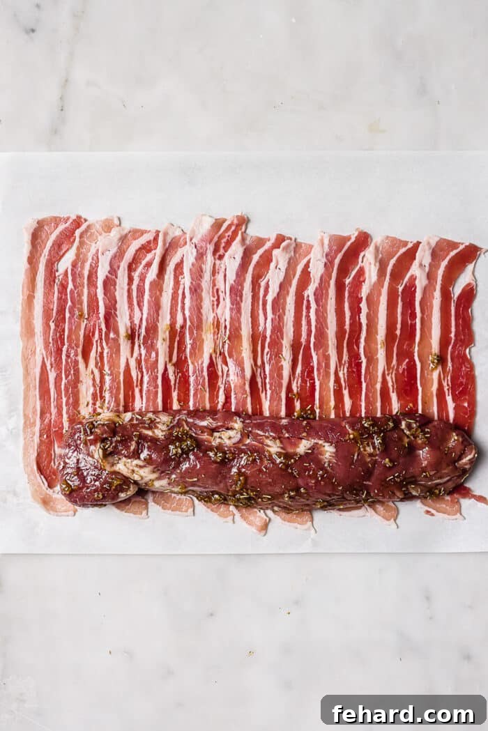 A tenderloin laying on top of several strips of bacon. 