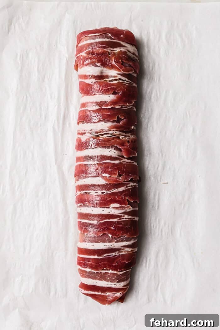 An overhead view of a bacon wrapped pork tenderloin. 