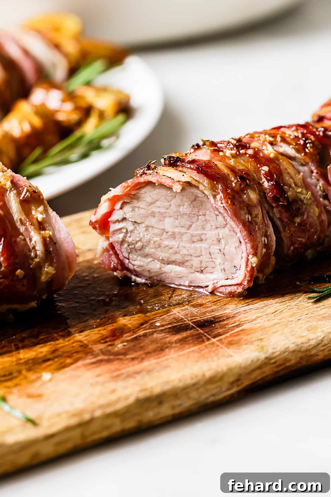 A side view of sliced pork tenderloin wrapped in bacon. 