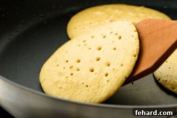 Oatmeal Pancakes being flipped over in skillet after small bubbles on surface formed.