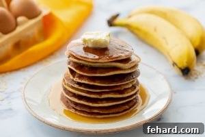 Stack of Blender Oat Pancakes on plate with bananas in back.