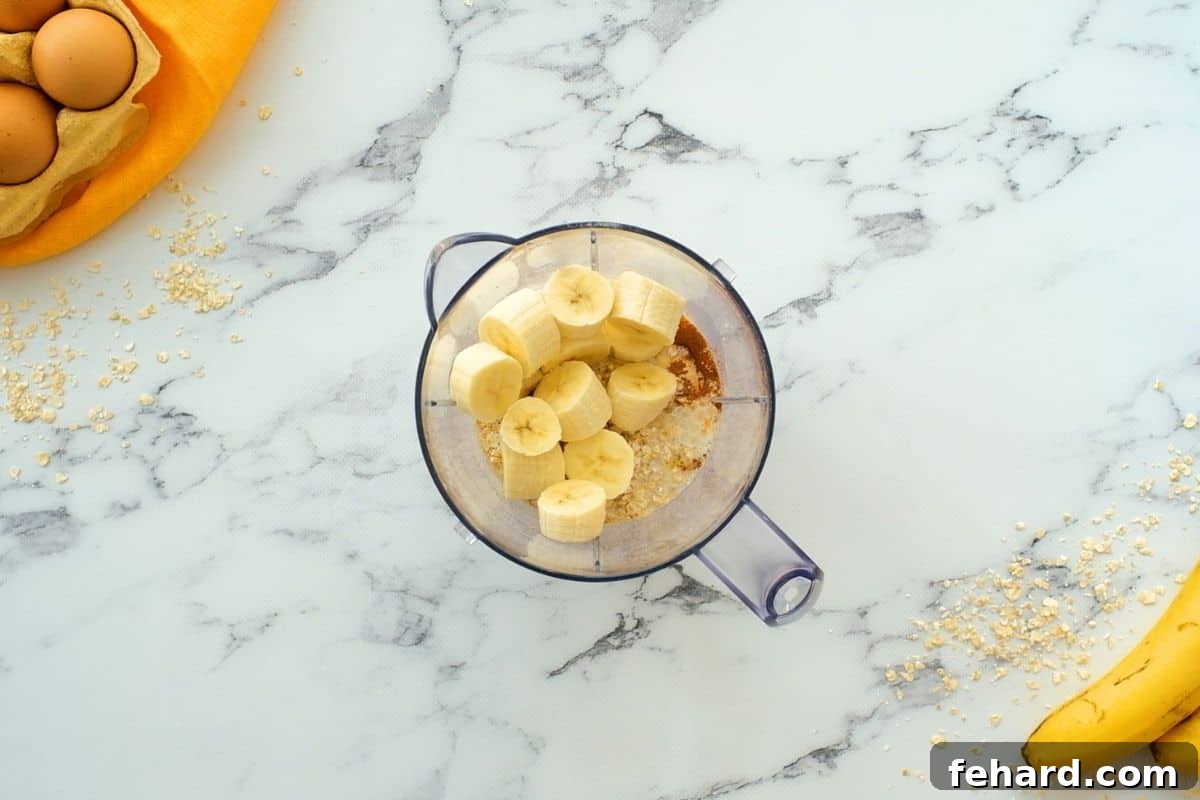 All the ingredients for banana oatmeal pancakes carefully layered in a blender, showing the proper order before blending for a smooth batter.
