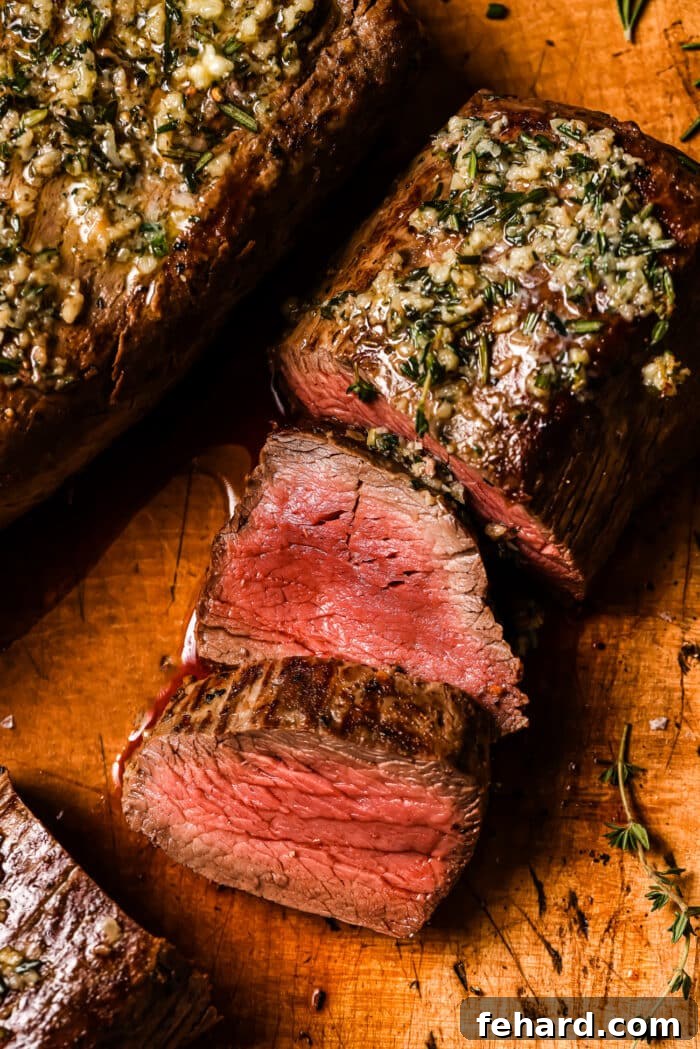 Golden Garlic Butter Tenderloin 9 Sliced beef on a wooden cutting board.