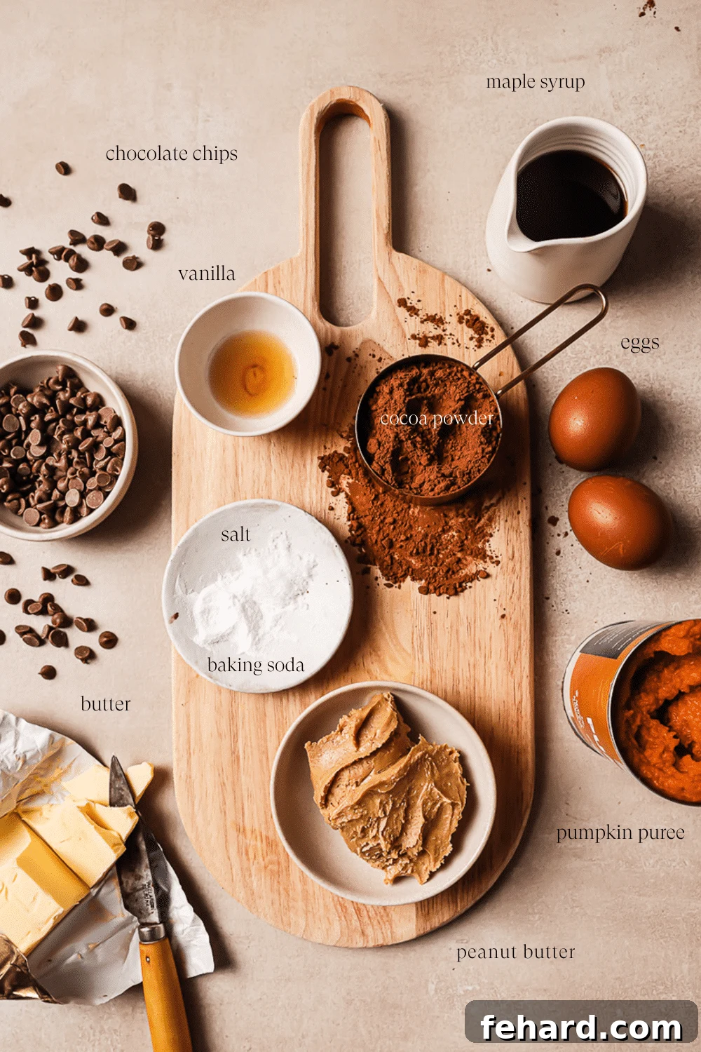 An overhead view of pre-measured ingredients on a wooden cutting board, ready for baking healthy pumpkin brownies.