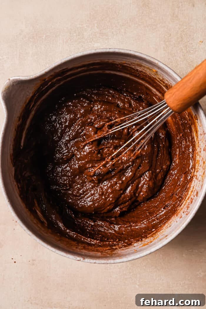 Peanut butter and pumpkin puree in a large bowl with a whisk in it, ready to be combined.