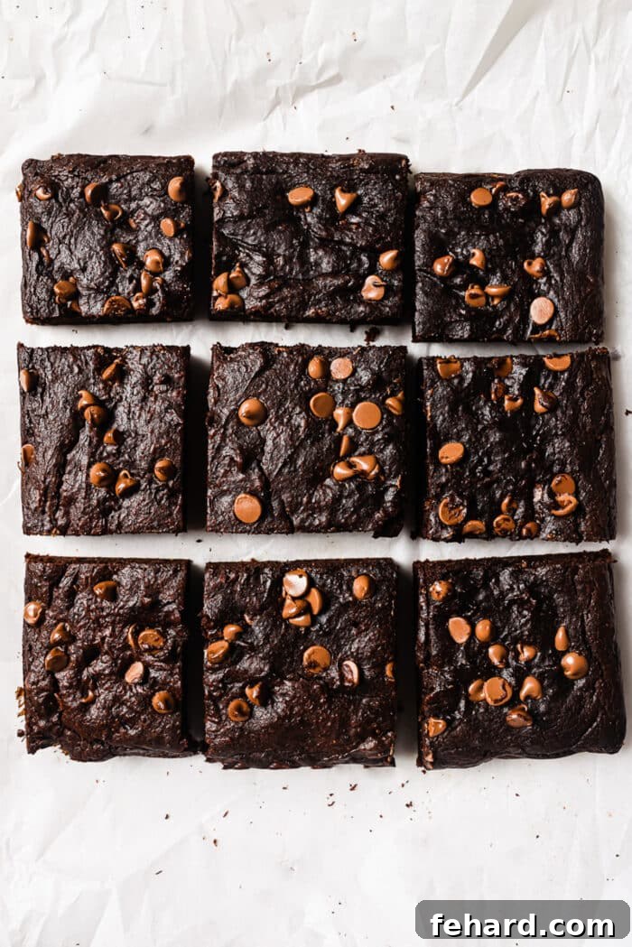 Healthy pumpkin brownies, freshly baked and cooled, cut into nine neat squares on a cutting board.