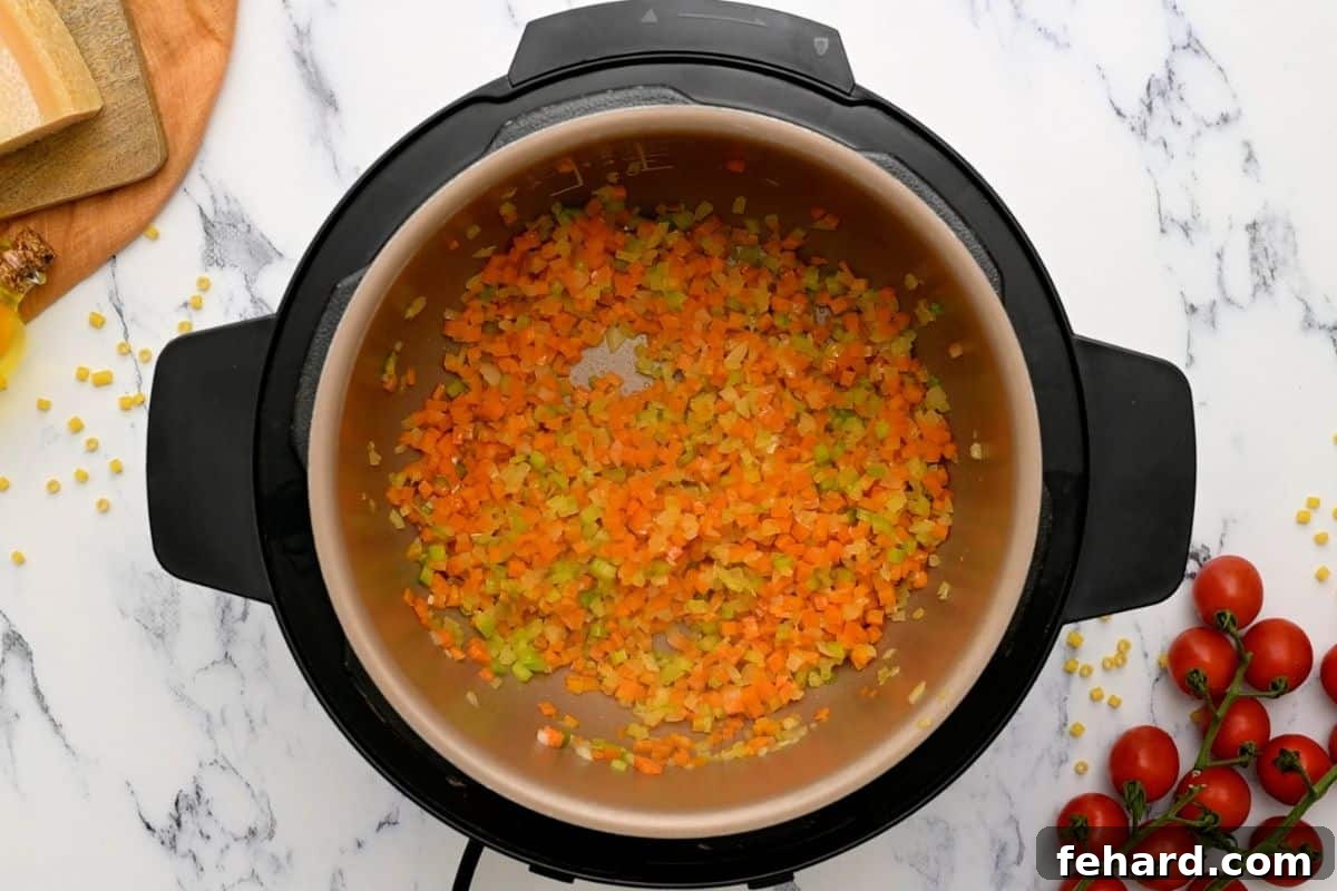 Pasta Fagioli Recipe Instant Pot Sautéed onions, carrots, and celery simmering in olive oil within the inner pot of an Instant Pot, creating a fragrant base for the soup.