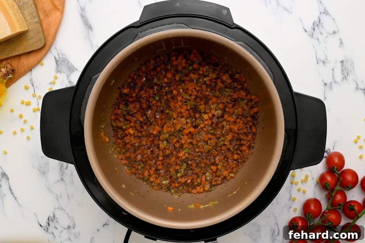Instant Pot Pasta Fagioli Recipe The Instant Pot's inner pot with sautéed aromatics being deglazed with red wine, the liquid bubbling as browned bits are scraped from the bottom.