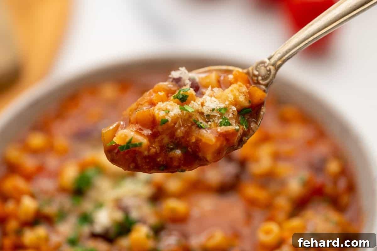 Recipe Instant Pot pasta fagioli A spoonful of Instant Pot Pasta Fagioli, rich with pasta and beans, generously topped with grated Parmesan cheese, ready to eat.
