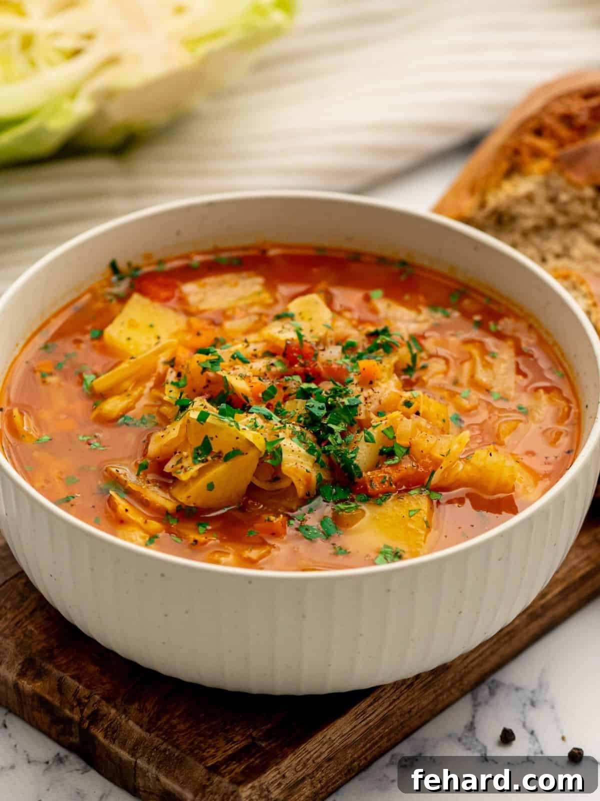 Instant Pot Cabbage Soup - Healthy & Easy Recipe Bowl of Instant Pot Cabbage Soup next to hearty rolls, garnished with fresh herbs.