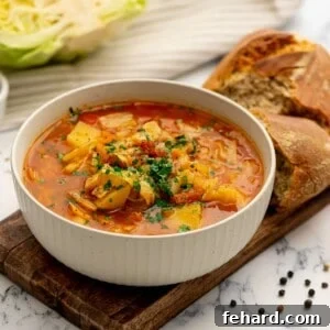 Bowl of Instant Pot Cabbage Soup next to hearty rolls.