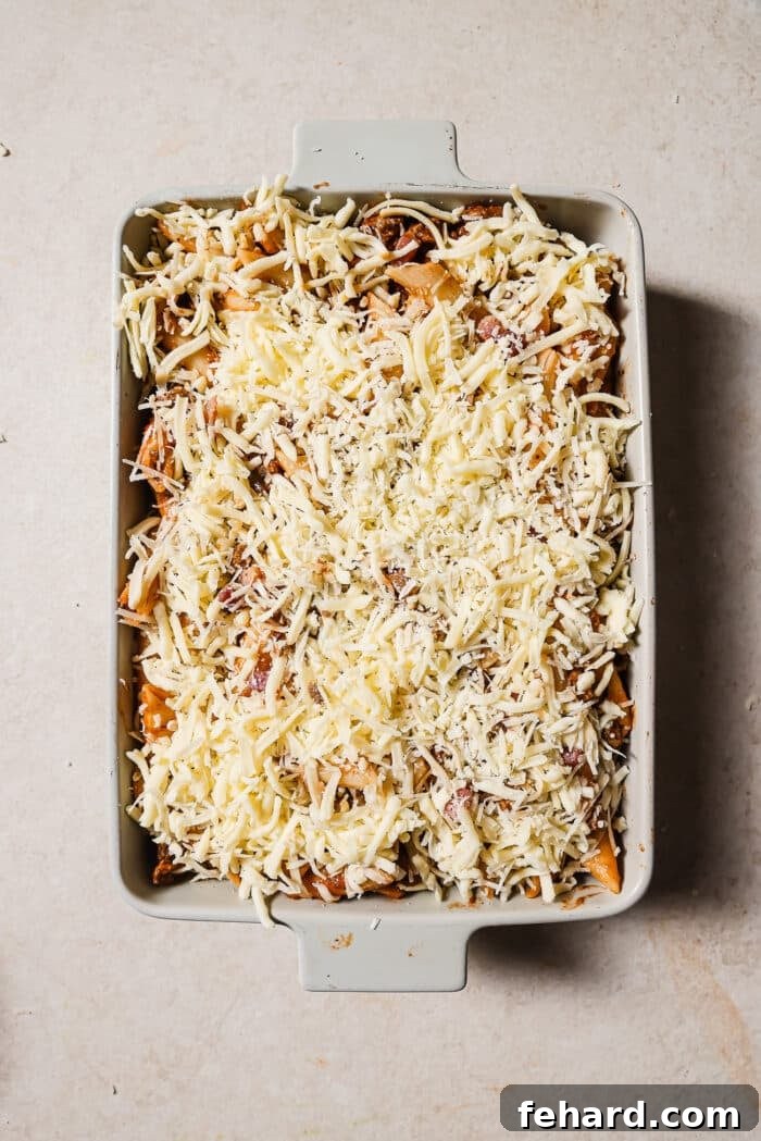 A white baking dish filled with baked ziti read to go into the oven. 