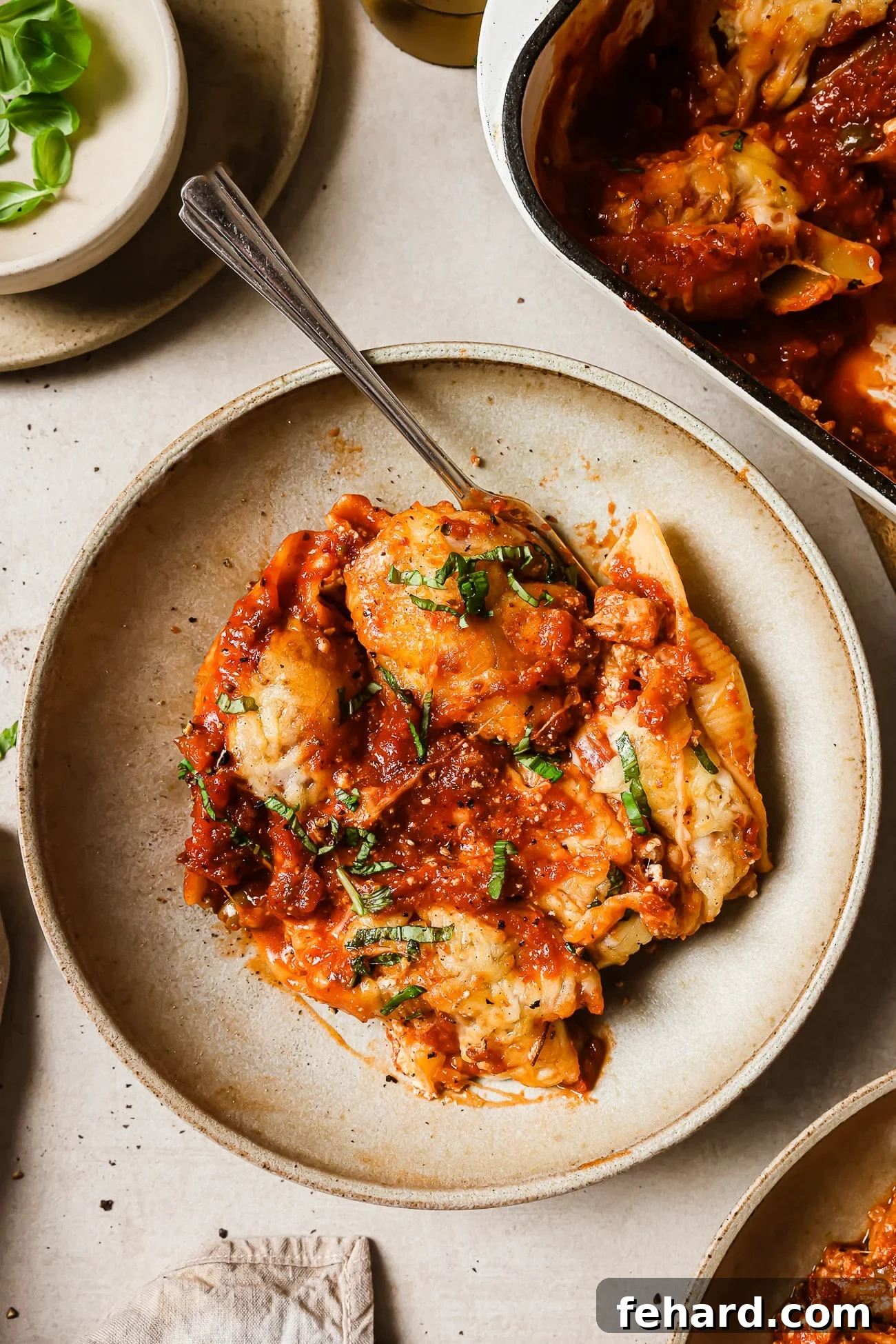 A serving of stuffed shells on a plate with a fork in it. 