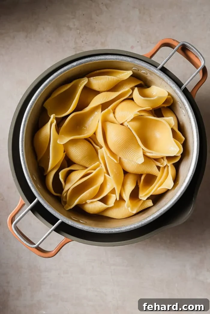 Cooked jumbo shell pasta draining in a colander. 