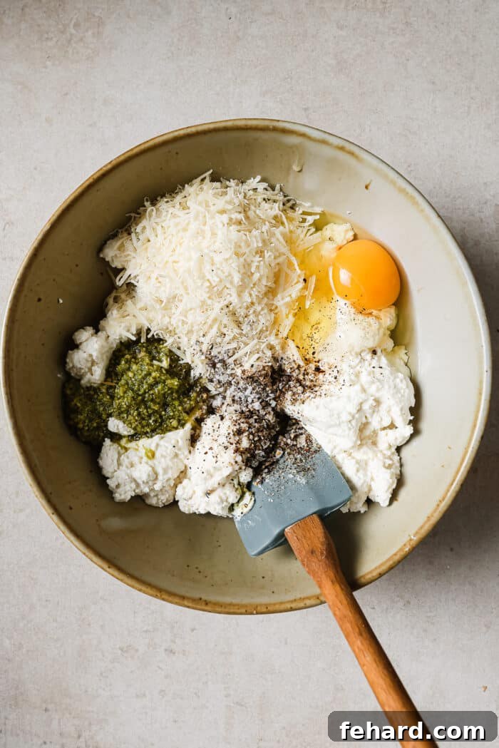 A bowl of ricotta and parmesan cheese, pesto, egg, salt, and pepper. 