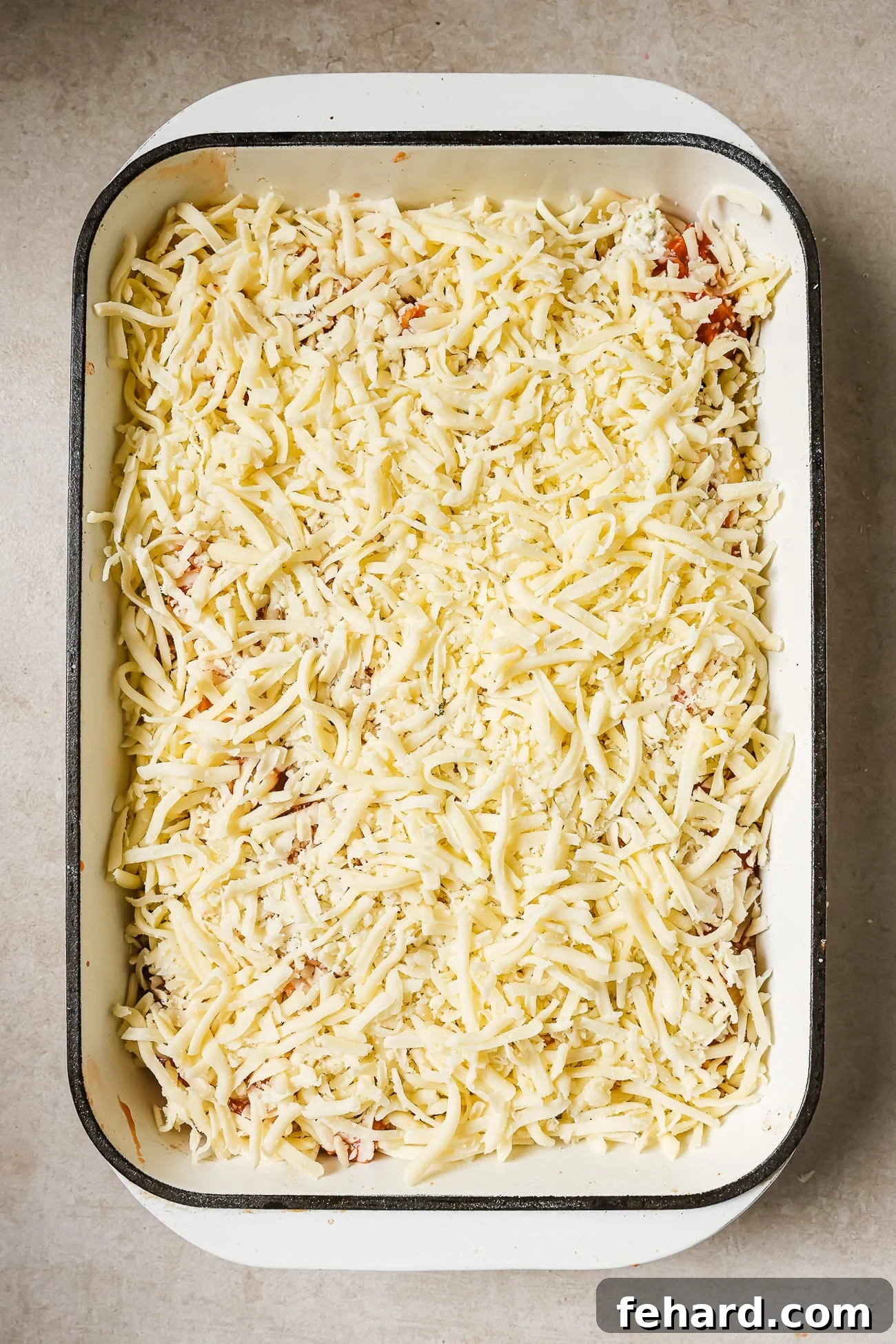 Stuffed shells topped with mozzarella cheese in a white casserole dish. 
