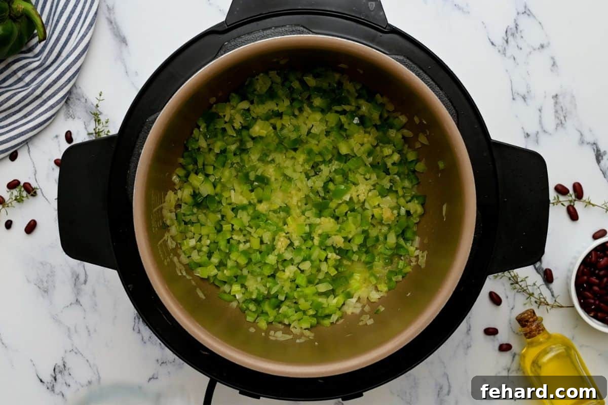 Diced bell peppers, onions, and celery (the Holy Trinity) sautéing in the Instant Pot alongside dried red beans.