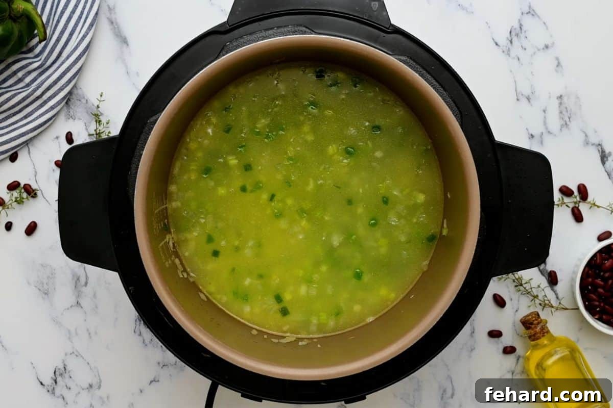 Liquid being added to the inner pot of the Instant Pot to deglaze, with sautéed peppers and onions visible.