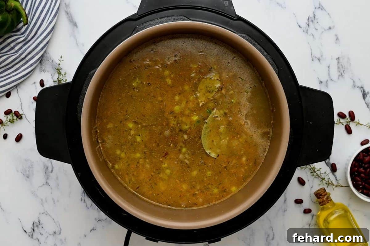 Ingredients for Instant Pot Red Beans and Rice, including beans, broth, and seasonings, layered inside the Instant Pot before pressure cooking.