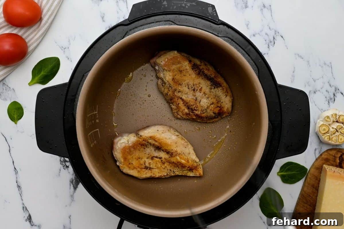 Instant Pot Creamy Chicken Seared seasoned chicken inside the Instant Pot inner pot, achieving a golden brown crust.