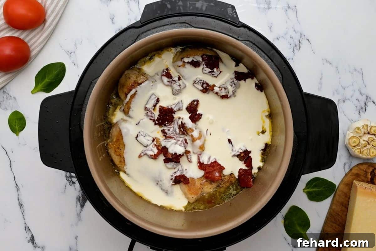 Instant Pot Chicken That Wins Hearts 3 Seared chicken breasts, heavy cream, chicken broth, and sun-dried tomatoes layered inside the Instant Pot before pressure cooking.
