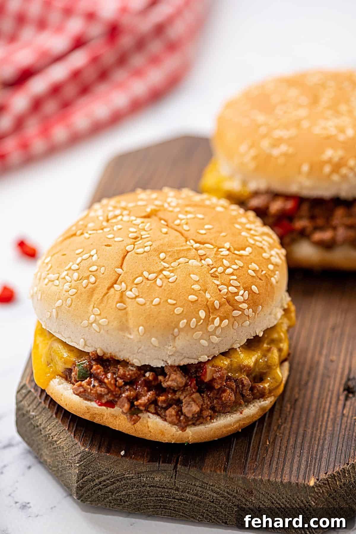 Two deliciously messy sloppy joes served on toasted buns on a rustic wooden cutting board, garnished with fresh cilantro.