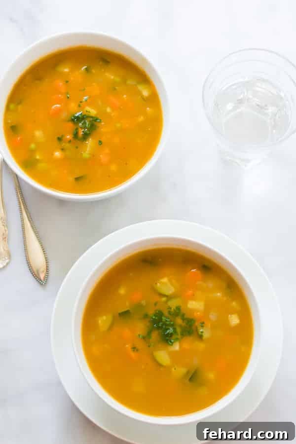 Two bowls of Zucchini Summer Soup served on a rustic wooden table.