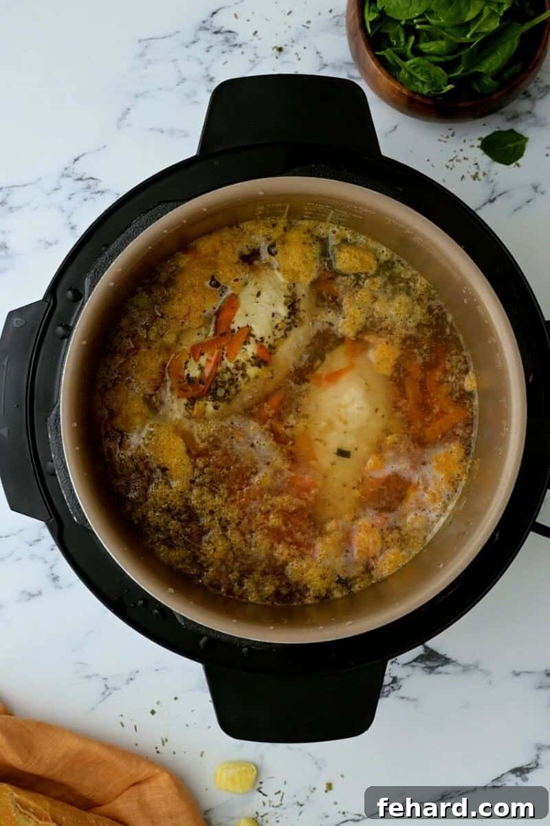 Poached chicken breasts in a rich broth inside the Instant Pot after pressure cooking and natural release.