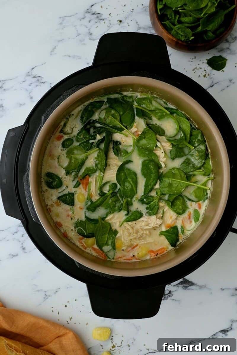 Instant Pot brimming with creamy chicken gnocchi soup, beautifully topped with fresh spinach.